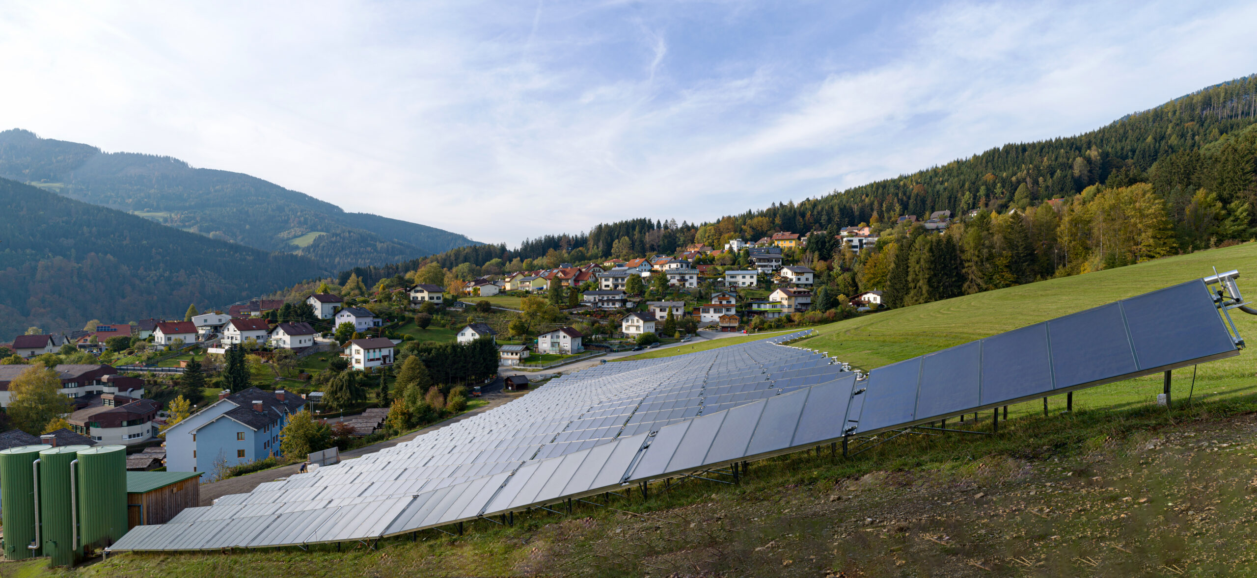 Solaranlage auf einem grünen Feld in Mürzzuschlag. Dahinter sieht man die Häuser der Stadtgemeinde.